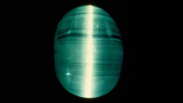 Gemma azzurra levigata con effetto luminoso centrale su sfondo nero