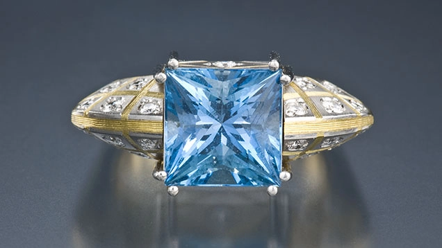 Anello con grande gemma azzurra taglio quadrato e dettagli decorativi sul gambo