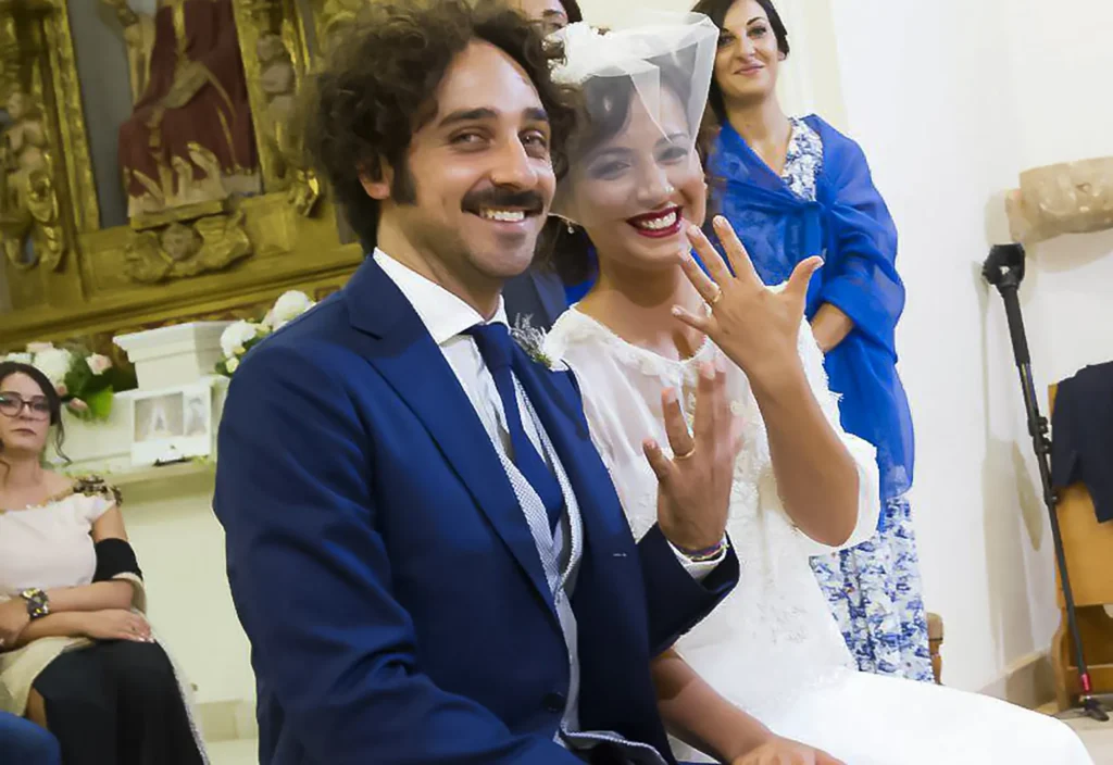 Sposi sorridenti mostrano le fedi nuziali personalizzate durante la cerimonia di matrimonio