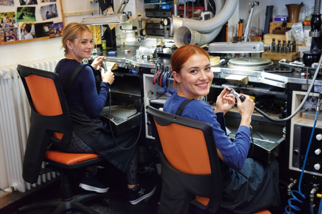 Two women sitting at the goldsmith’s bench during a craft experience to create bespoke jewellery and wedding rings.