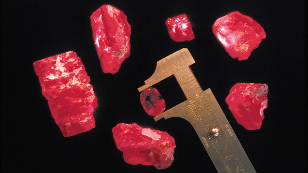 Raw red ruby fragments next to a scale bar