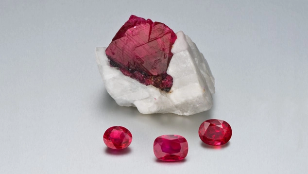 Raw ruby crystal with three faceted red rubies