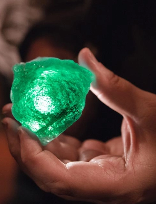Smeraldo grezzo verde tenuto in mano